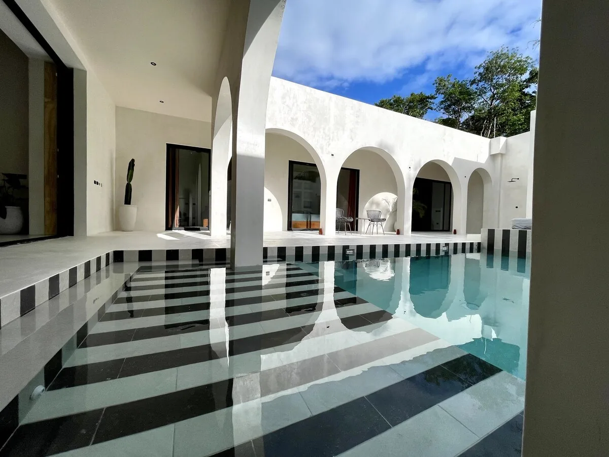 Casa Bali área de alberca de lujo con jardín tropical y arquitectura minimalista