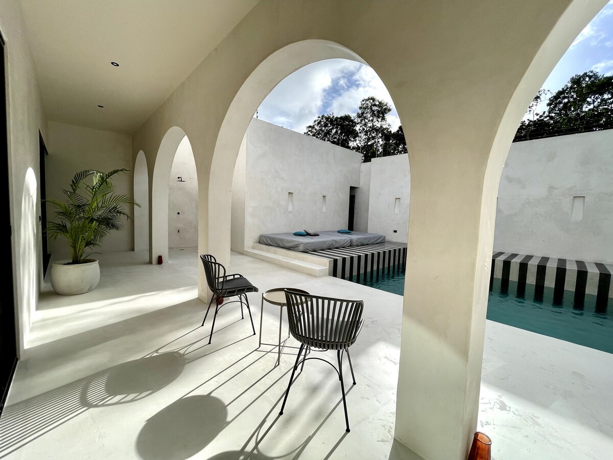 Casa Bali suite principal con cama king y vistas al jardín tropical en Tulum